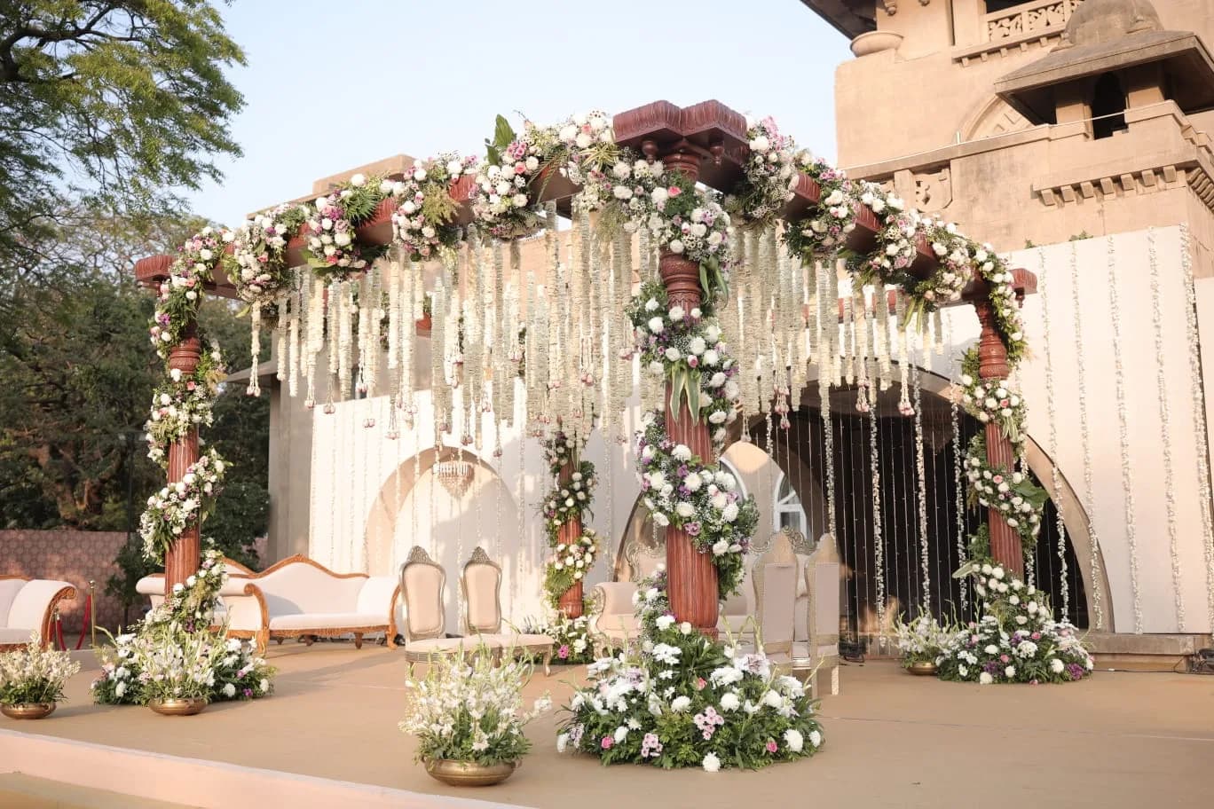 Wooden mandap pillars dressed in white and pink florals at Shivmahal Palace