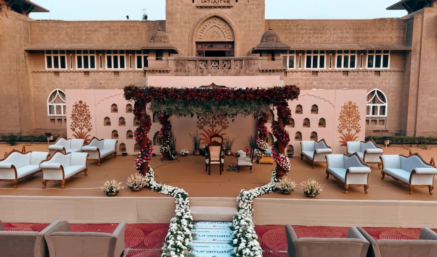 Mandap in maroon and pink florals with lounge seating at Shivmahal Palace, Vadodara