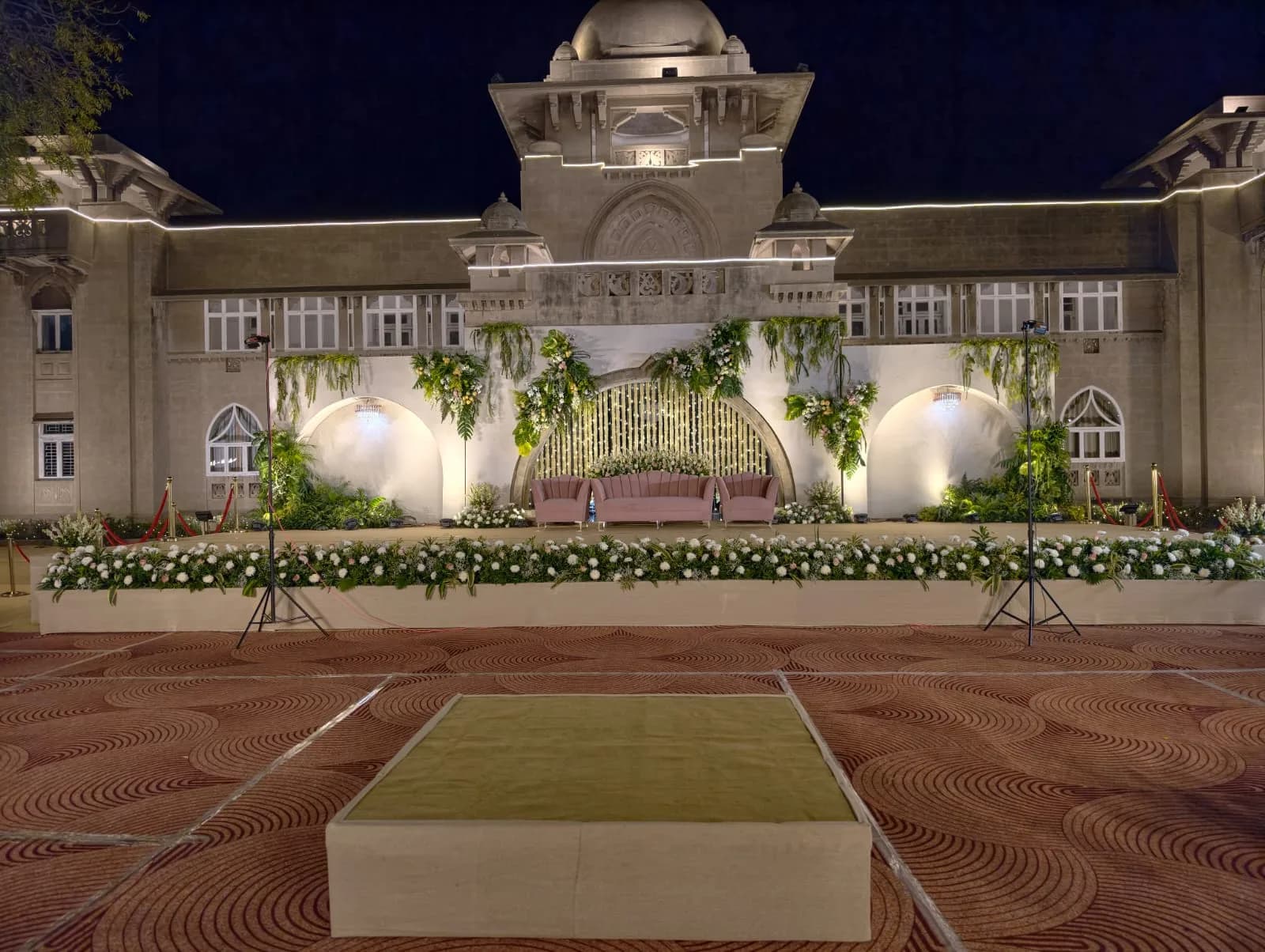 Reception stage with blush sofas and a foliage backdrop at Shivmahal Palace