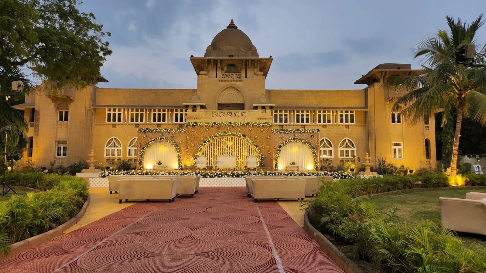 Reception stage set against a floral wall with the palace behind at Shivmahal Palace