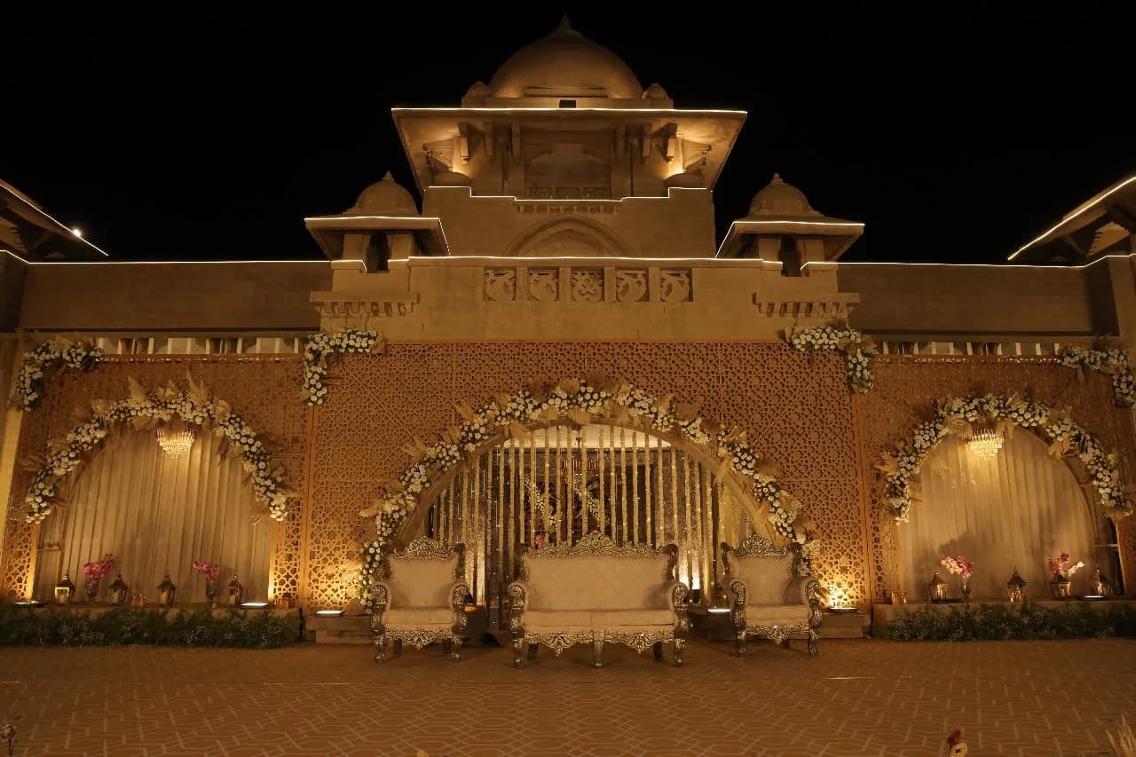 Reception stage with a jali backdrop and carved sofas at Shivmahal Palace, Vadodara
